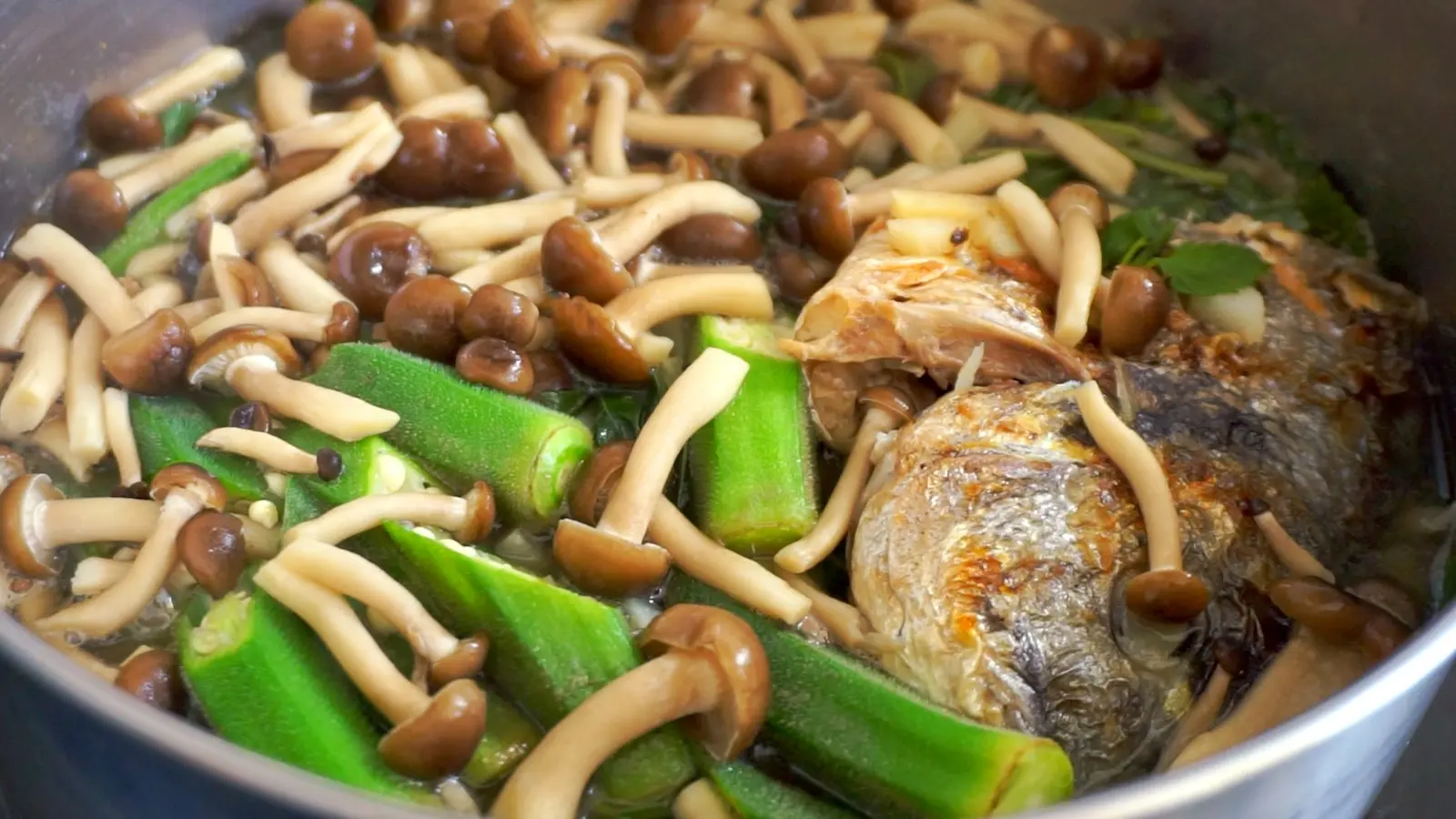 Grilled fish, saluyot, labong, okra, and shimeji mushrooms simmering in a bagoong broth