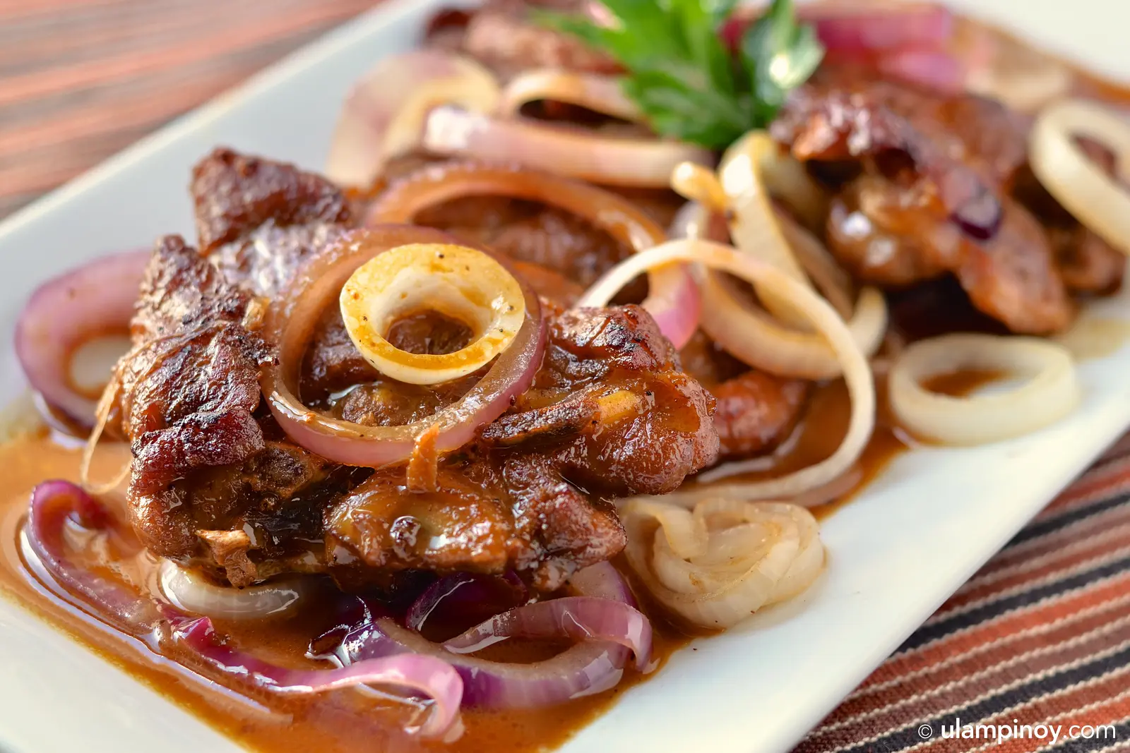 Pork bistek plated with onion rings and sauce