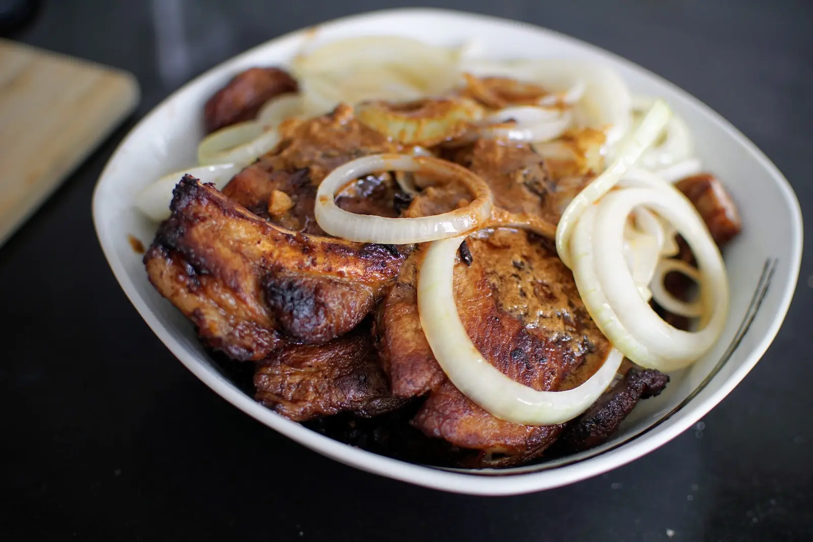 Pork Bistek served in a bowl with onion rings and sauce